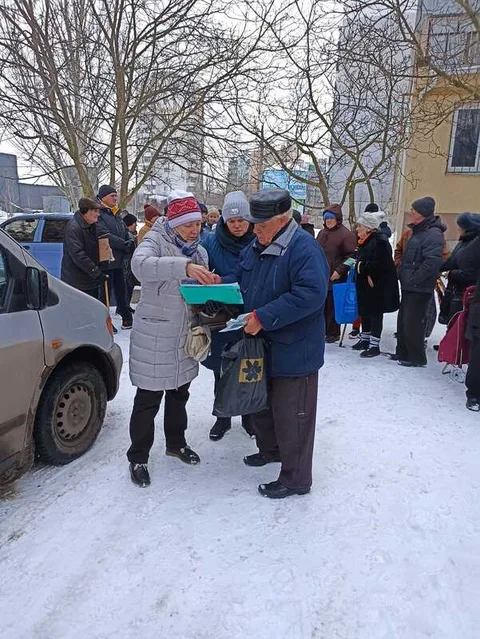 People receiving supplies outside a building in snow