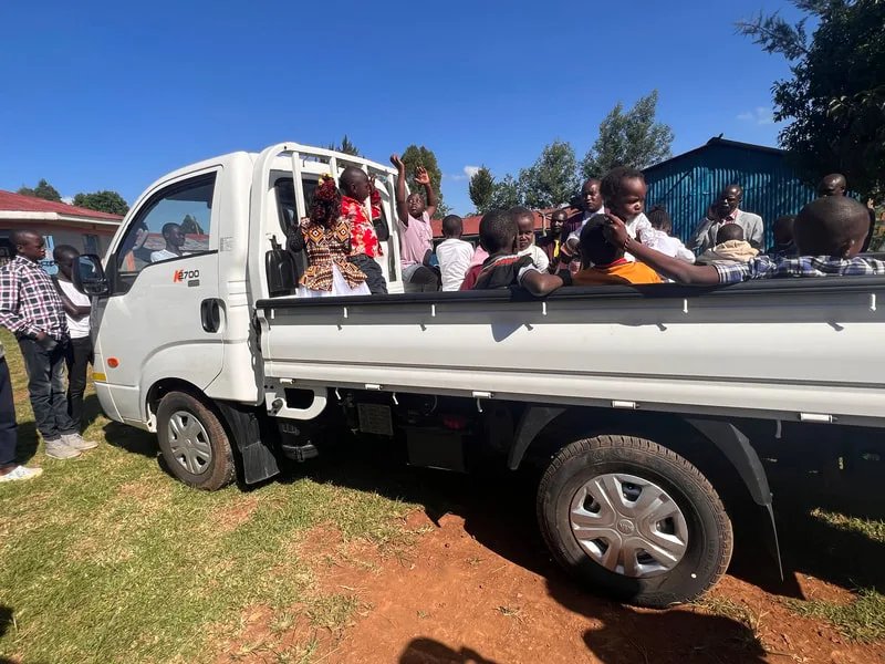 Passengers seated in a white flatbed truck