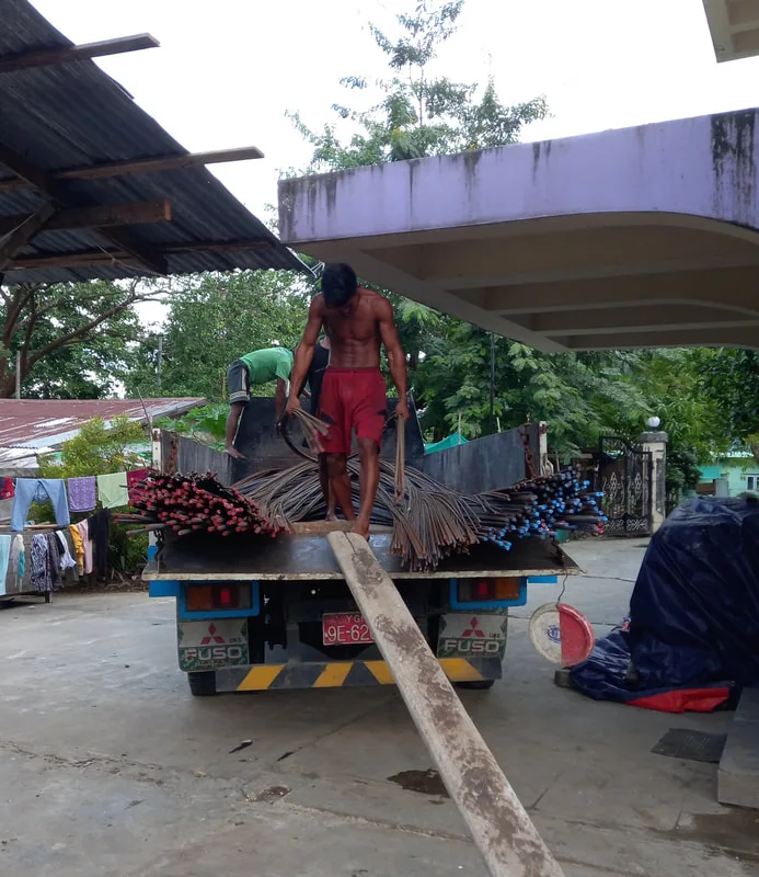 Worker standing on a truck bed beside timber