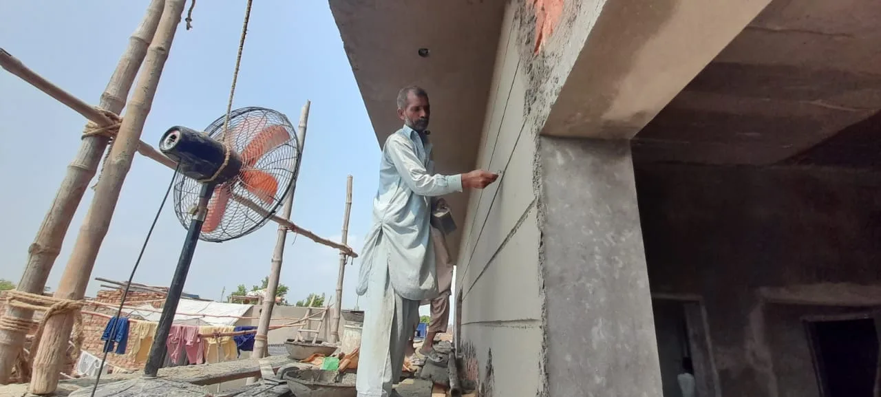 Worker plastering an upper wall