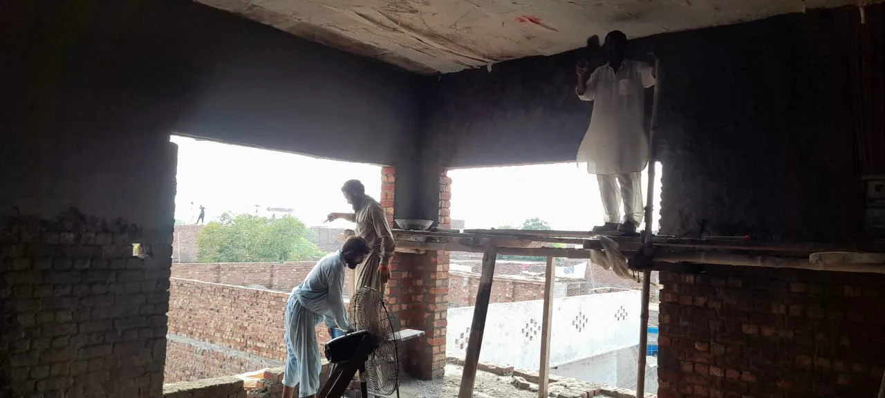 Worker plastering an interior wall from scaffolding