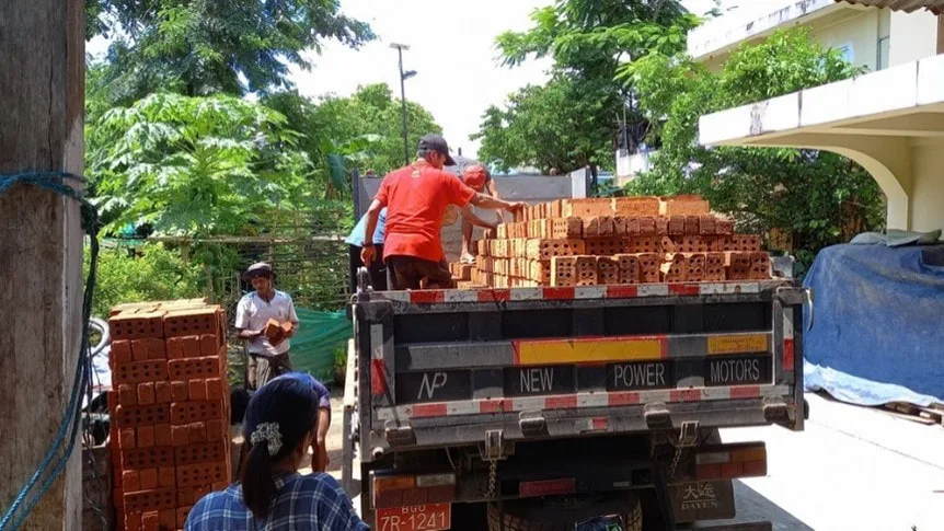 Workers unloading bricks from a truck