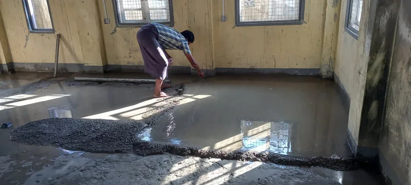 Worker spreading concrete over a floor
