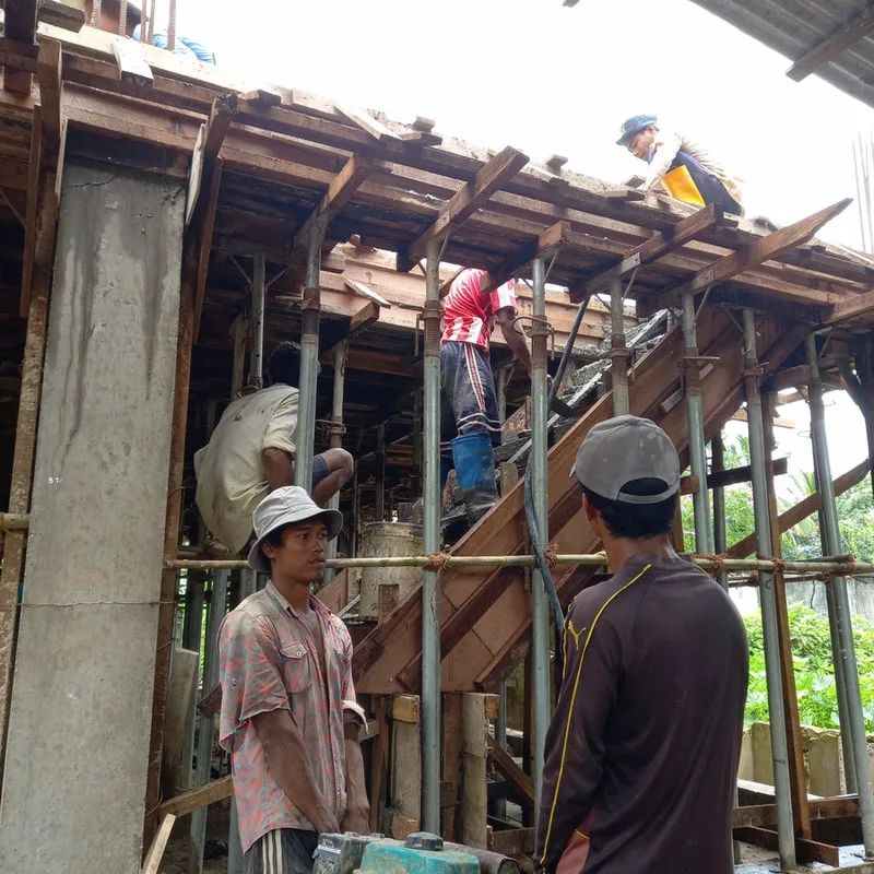 Workers pouring concrete beside a staircase