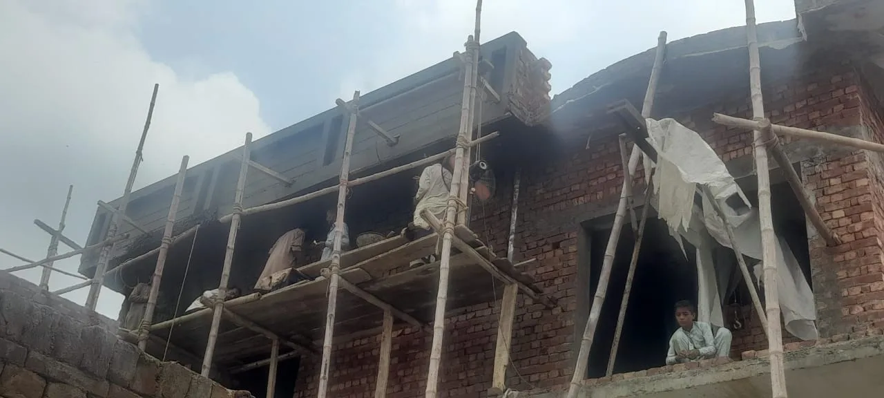 Workers on scaffolding outside a brick building