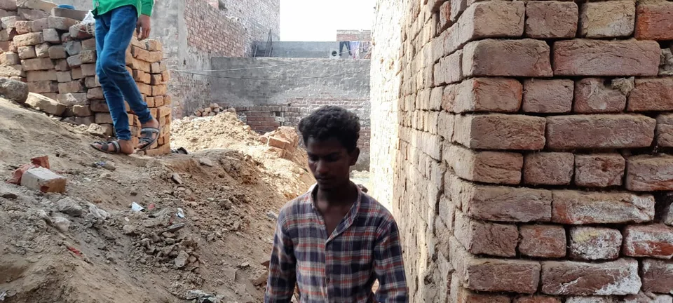 Worker standing in a trench beside a brick wall