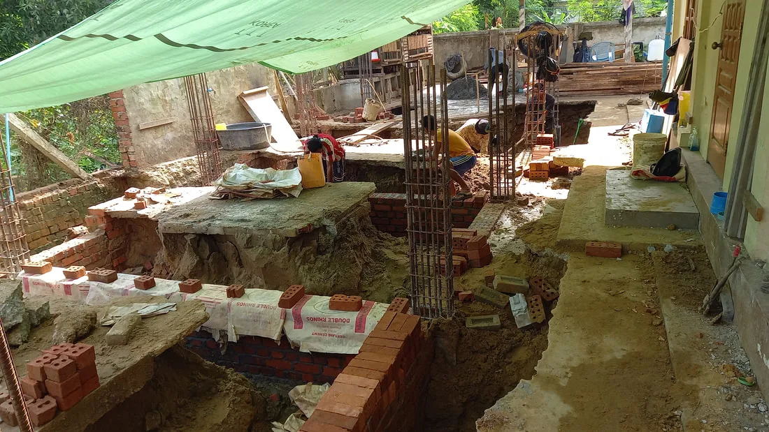Foundation trenches and building supplies beneath a canopy