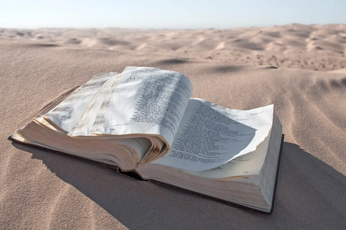 Open Bible resting on sand
