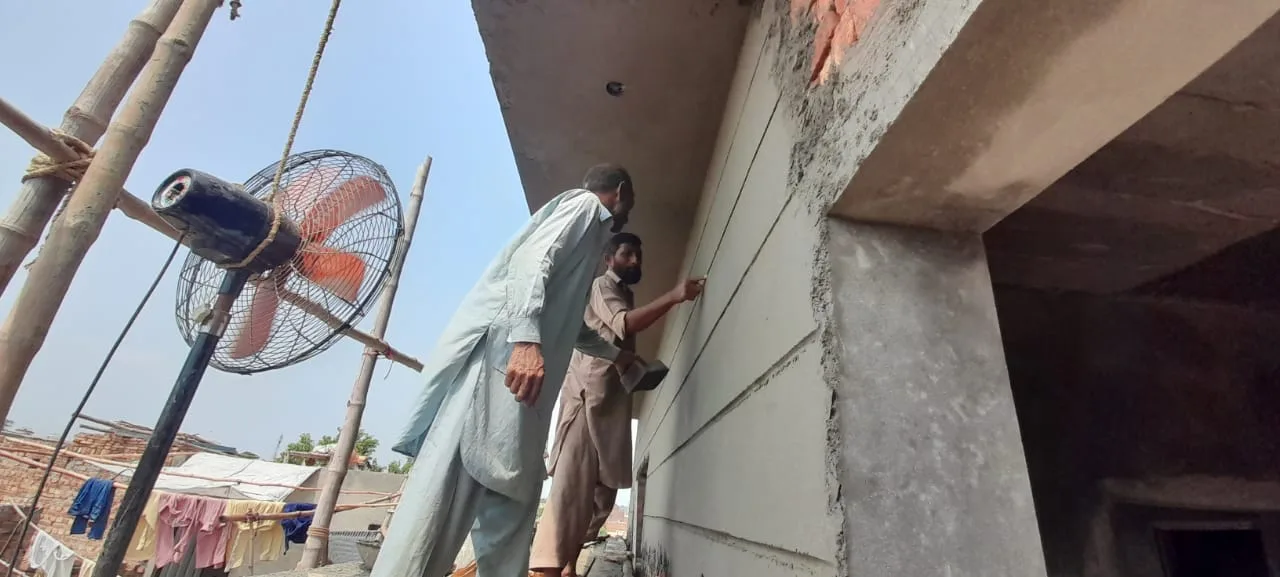 Worker finishing plaster beside a doorway