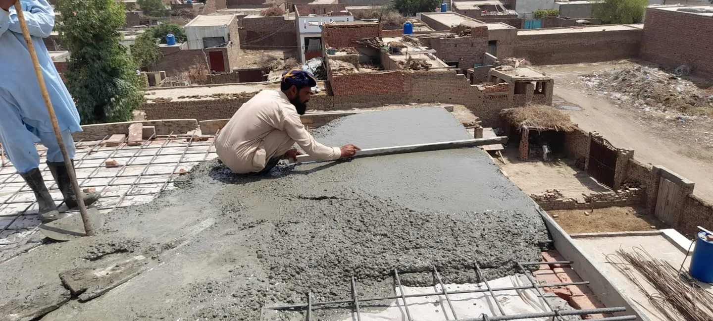 Workers spreading concrete over a roof slab