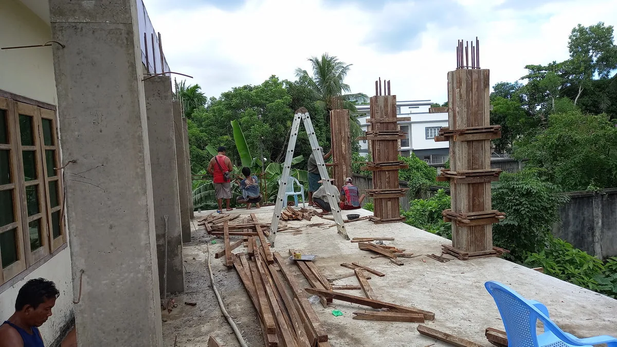 Workers fitting formwork around concrete columns