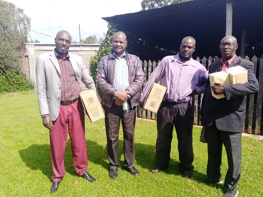Four men standing outside holding books