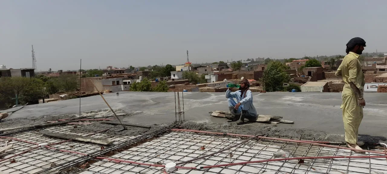 Workers spreading concrete over roof reinforcement